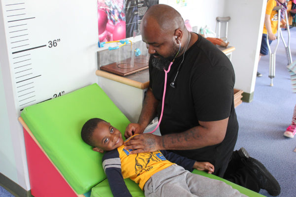 A father and his son playing together in the doctor area of the careers section at the Kansas Children's Discovery Center.